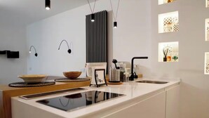 Cozinha moderna com bancada branca, torneira preta e luminárias pendentes.