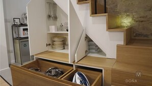 Uma cozinha moderna com armários de madeira, micro-ondas embutido e área de armazenamento com portas de vidro.
