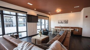 Un salon moderne avec un canapé, un coin repas et de grandes fenêtres.