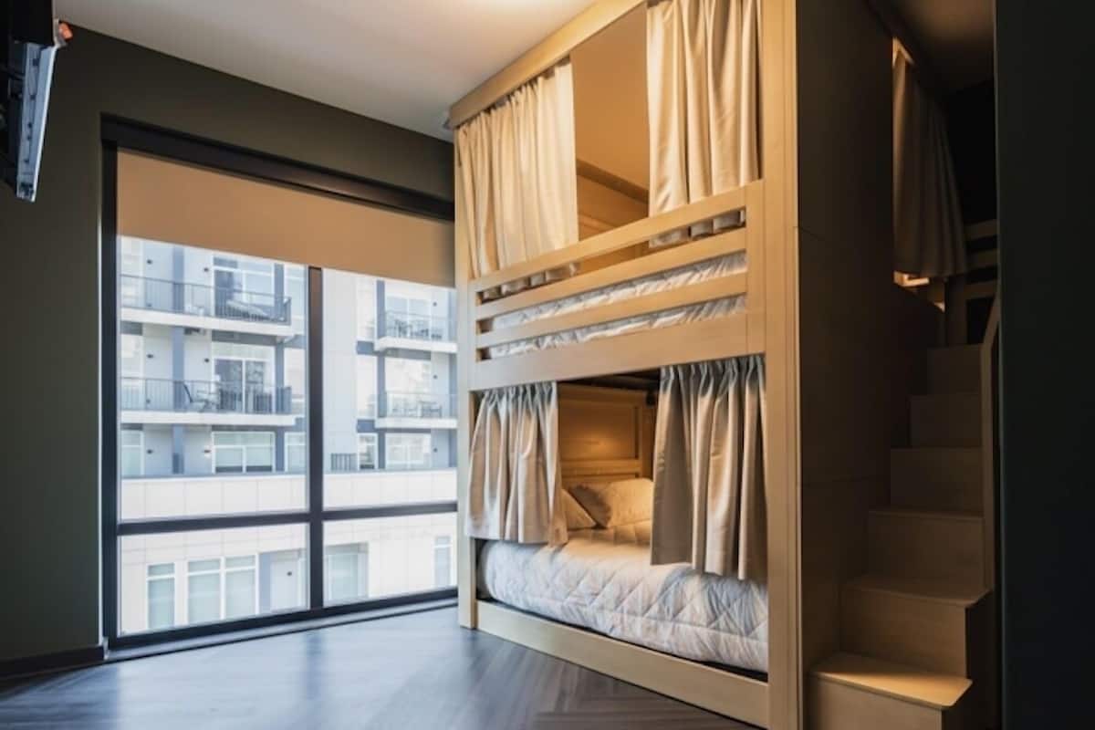 Ein Zimmer mit Etagenbett, großen Fenstern und einer Treppe.