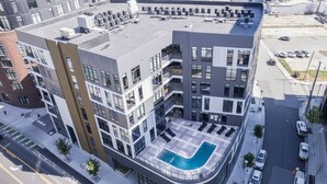 Un bâtiment moderne doté d’une piscine sur le toit, d’une promenade piétonne et offrant une vue sur la rue.