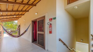 A hallway with a hammock, a fire extinguisher, and a staircase leading to a balcony. - Casa Vento - Your Exclusive Refuge by Carpediem (Caucaia)