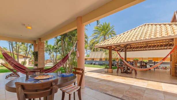 A covered outdoor dining area with a table, chairs, and a hammock. - Casa Vento - Your Exclusive Refuge by Carpediem (Caucaia)