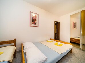 Ein Schlafzimmer mit zwei Einzelbetten, einem Holzkopfstück, einem gerahmten Bild an der Wand und einem Spiegel in der Ecke.