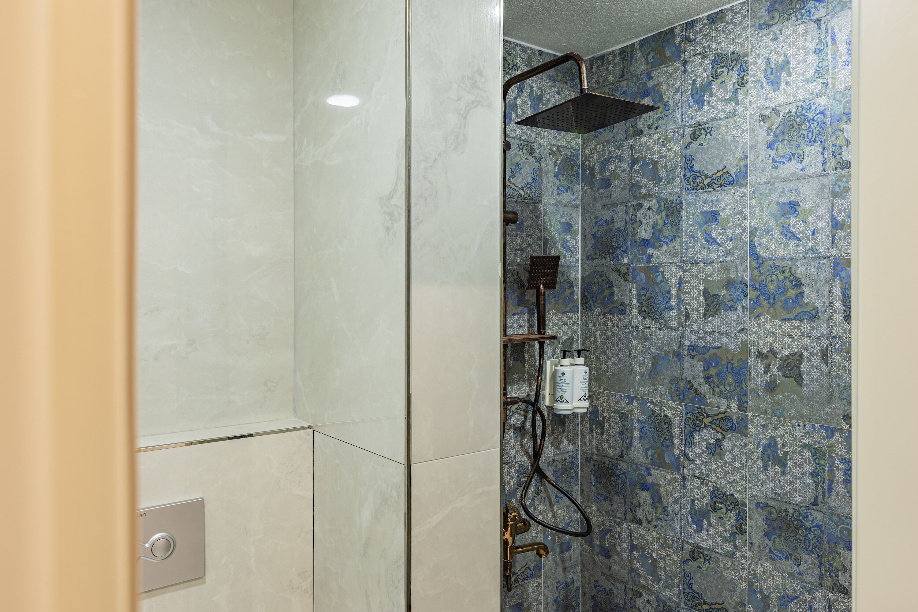 A shower with a rain showerhead, a handheld showerhead, and a control panel.