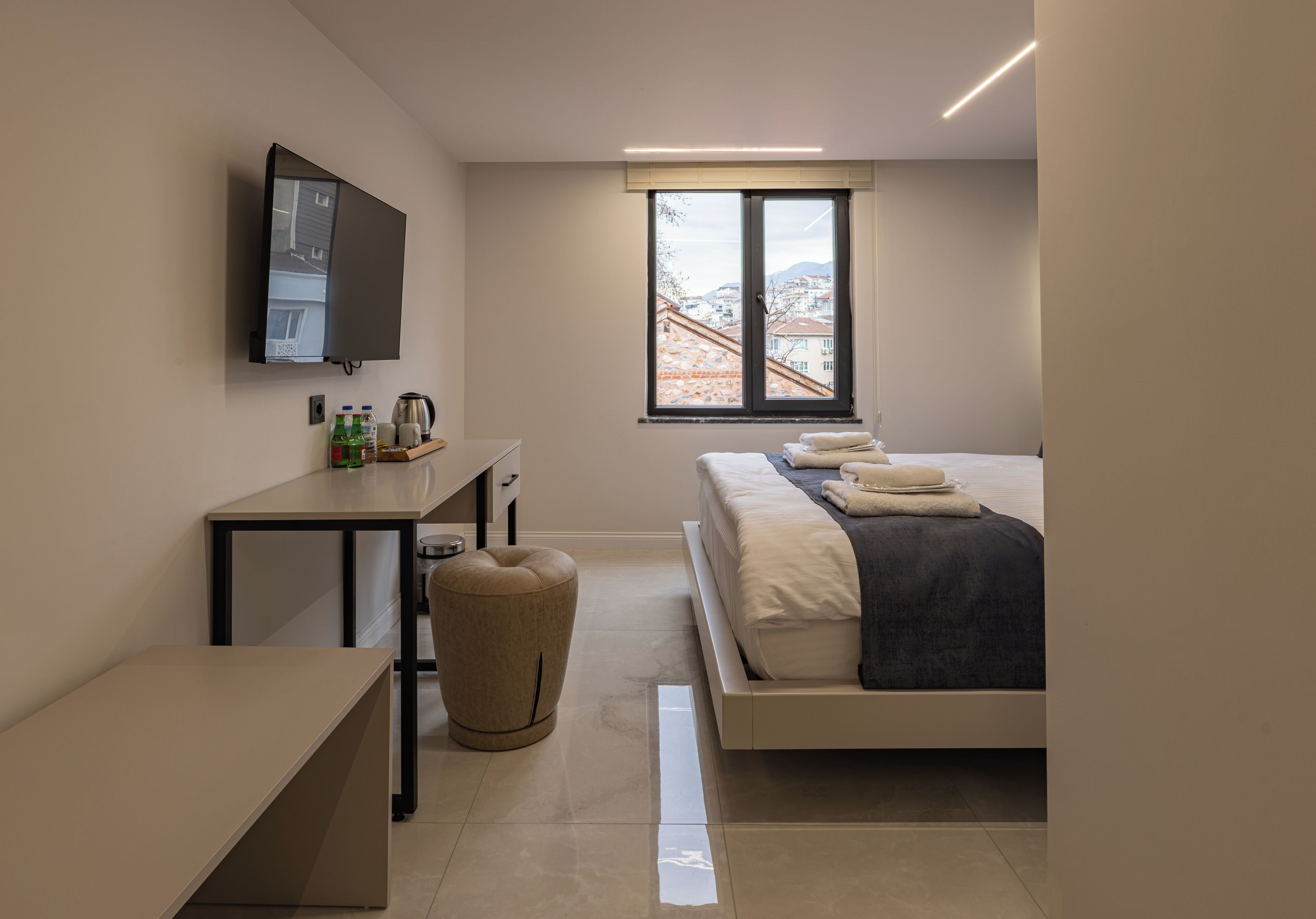 Un dormitorio moderno con cama, mesita de noche y televisor montado en la pared.