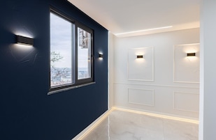 Un pasillo con un ventanal grande, iluminación empotrada en la pared y suelo de baldosas.