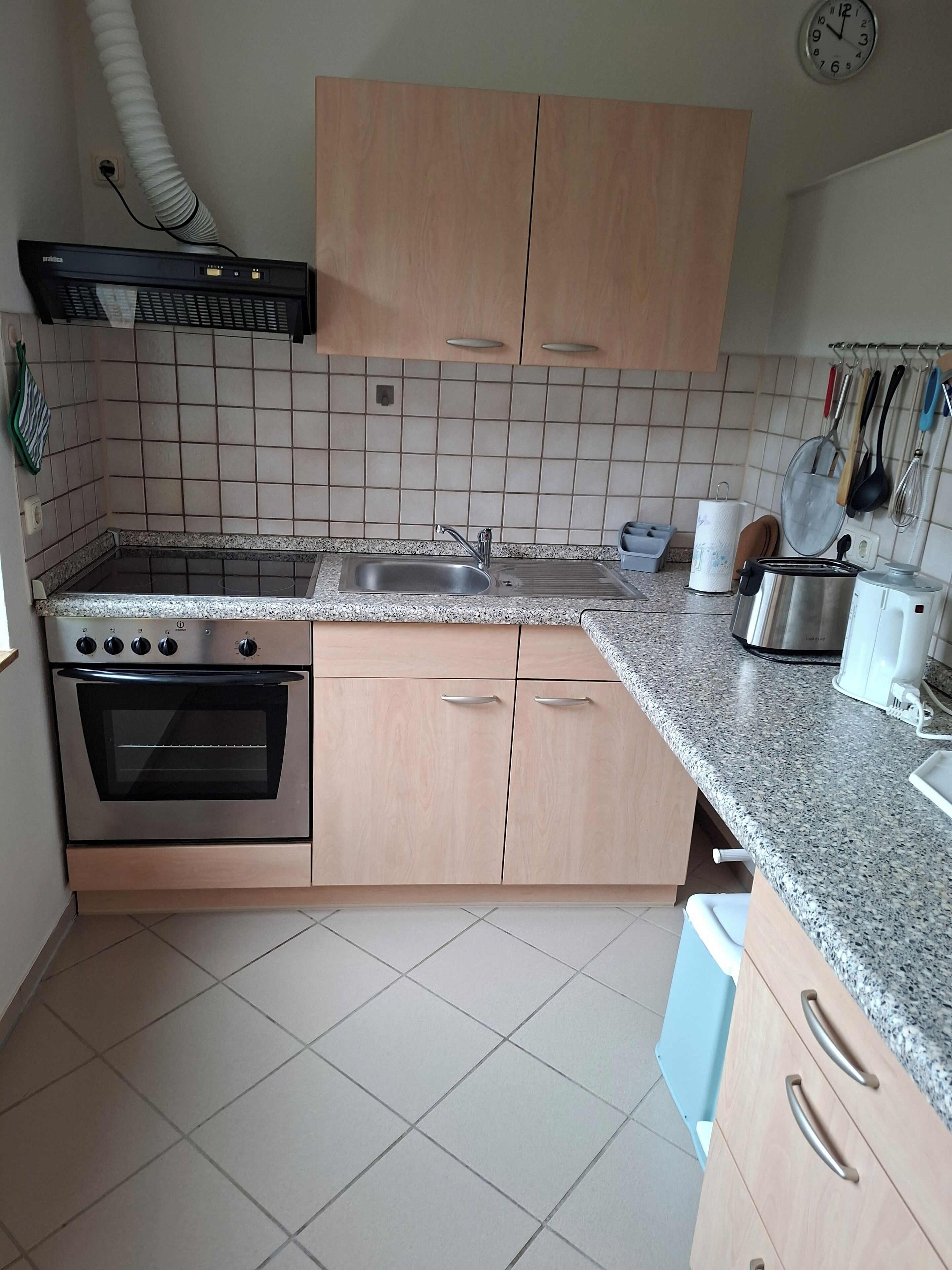 Een keuken met een roestvrijstalen oven, een spoelbak en houten kastjes.