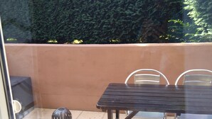 A patio with a table and chairs, a decorative vase, and a hedge in the background. - Vacation apartment Zülpich-Nähe Seepark (Zülpich)