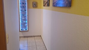 A hallway with a tiled floor, a wall-mounted shelf with shoes, and three framed pictures. - Vacation apartment Zülpich-Nähe Seepark (Zülpich)