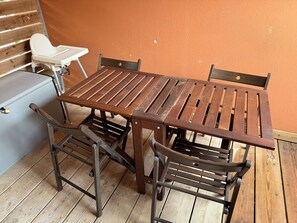 A wooden table with metal chairs, a white chair, and a grey cabinet in a room with an orange wall. - First floor apartment in Lecci, Corsica (Lecci)