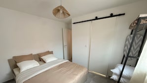 Een slaapkamer met een bed, een kledingkast, een hangrek en een hanglamp.