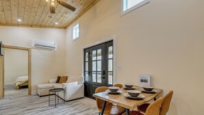 Ein modernes Wohnzimmer mit Essbereich, Holzboden, einer Couch, einem Couchtisch und einem Esstisch mit Stühlen.
