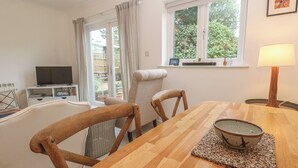 A dining area with a wooden table, chairs, and a bowl on a placemat. - Pump Cottage (Truro)