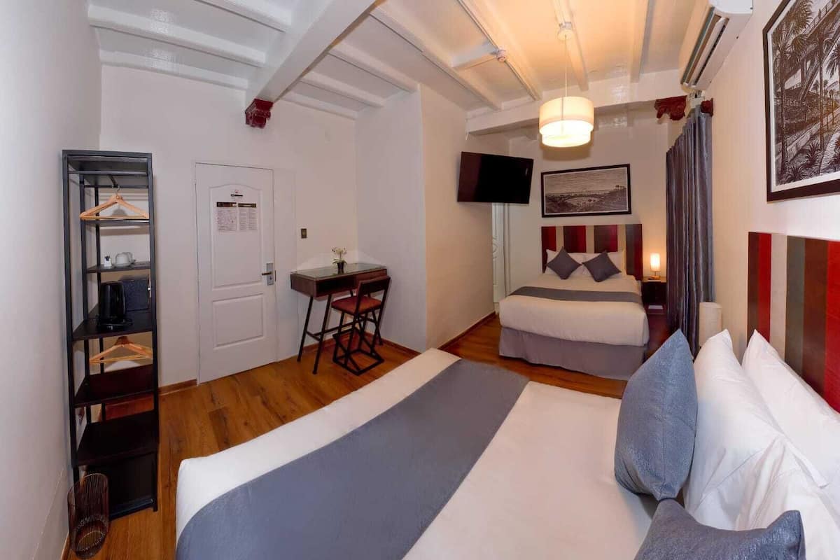 Una habitación de hotel con cama, escritorio, silla, televisión y un cuadro en la pared.