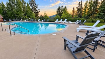 Une piscine avec des chaises longues et une terrasse en béton.