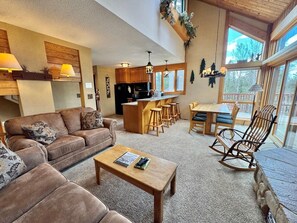A cozy living room with a sofa, coffee table, and a kitchen area with bar stools.