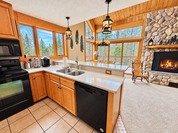 A modern kitchen with wooden cabinets, a dishwasher, a stove, and a stone fireplace.