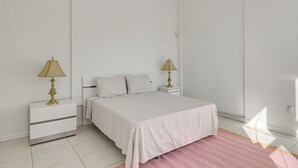 Un dormitorio con una cama, dos mesitas de noche y lámparas.