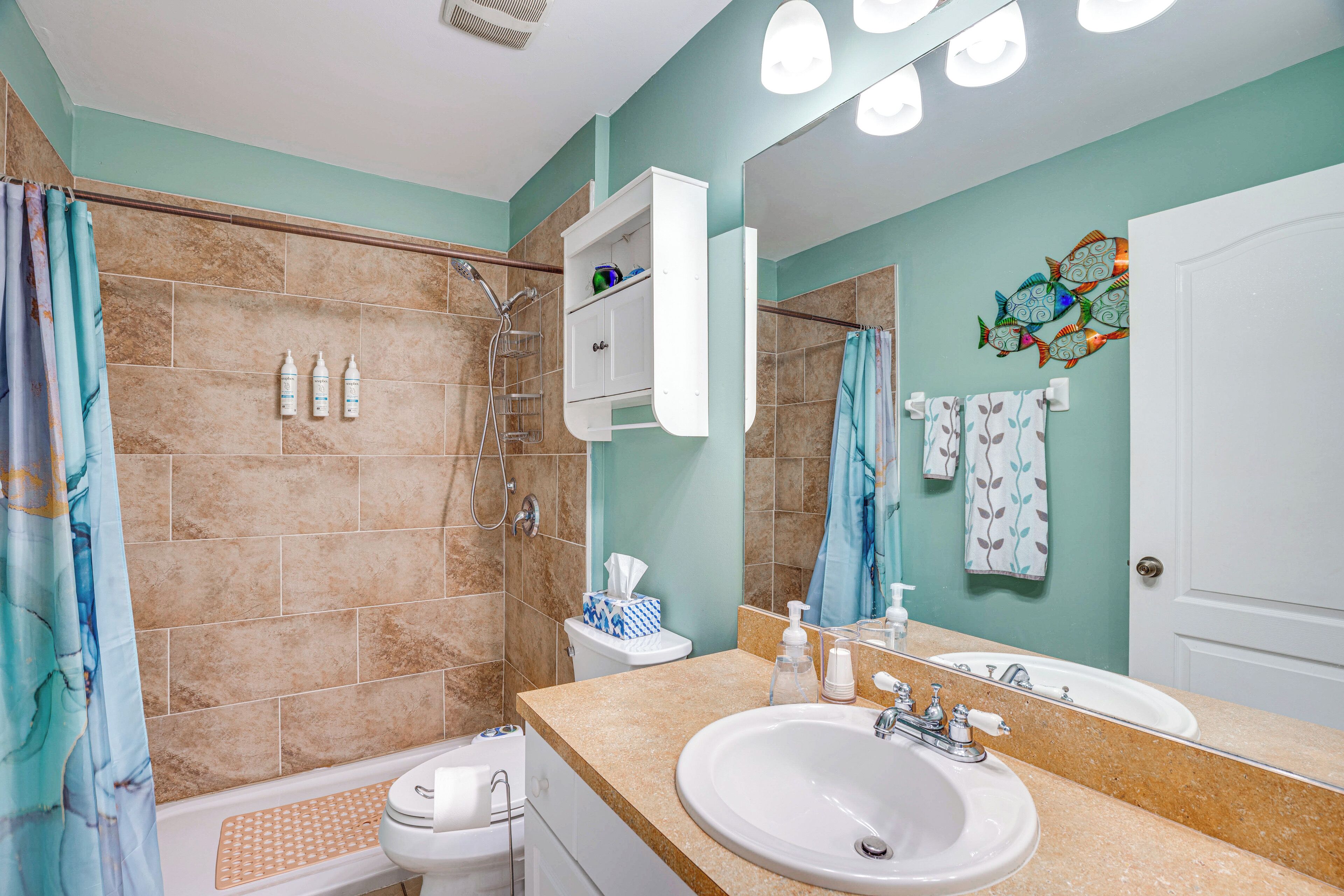 Ein Badezimmer mit Waschbecken, Spiegel, Dusche und Toilette.