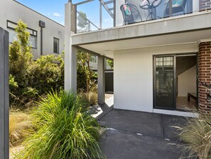 Ein modernes Gebäude mit flachem Dach, großen Fenstern und einem Balkon mit Sitzgelegenheit im Freien.