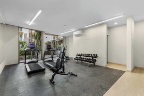 A gym with treadmills, a stationary bike, and a bench with dumbbells. - Las Arenas 1BR | Pool, Jacuzzi, Near Beach (Cabo San Lucas)