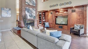 A spacious living room with a sectional sofa, a fireplace, wooden cabinets, and a flat-screen TV. - Super Private Vegas Retreat! Close to Strip! (Las Vegas)