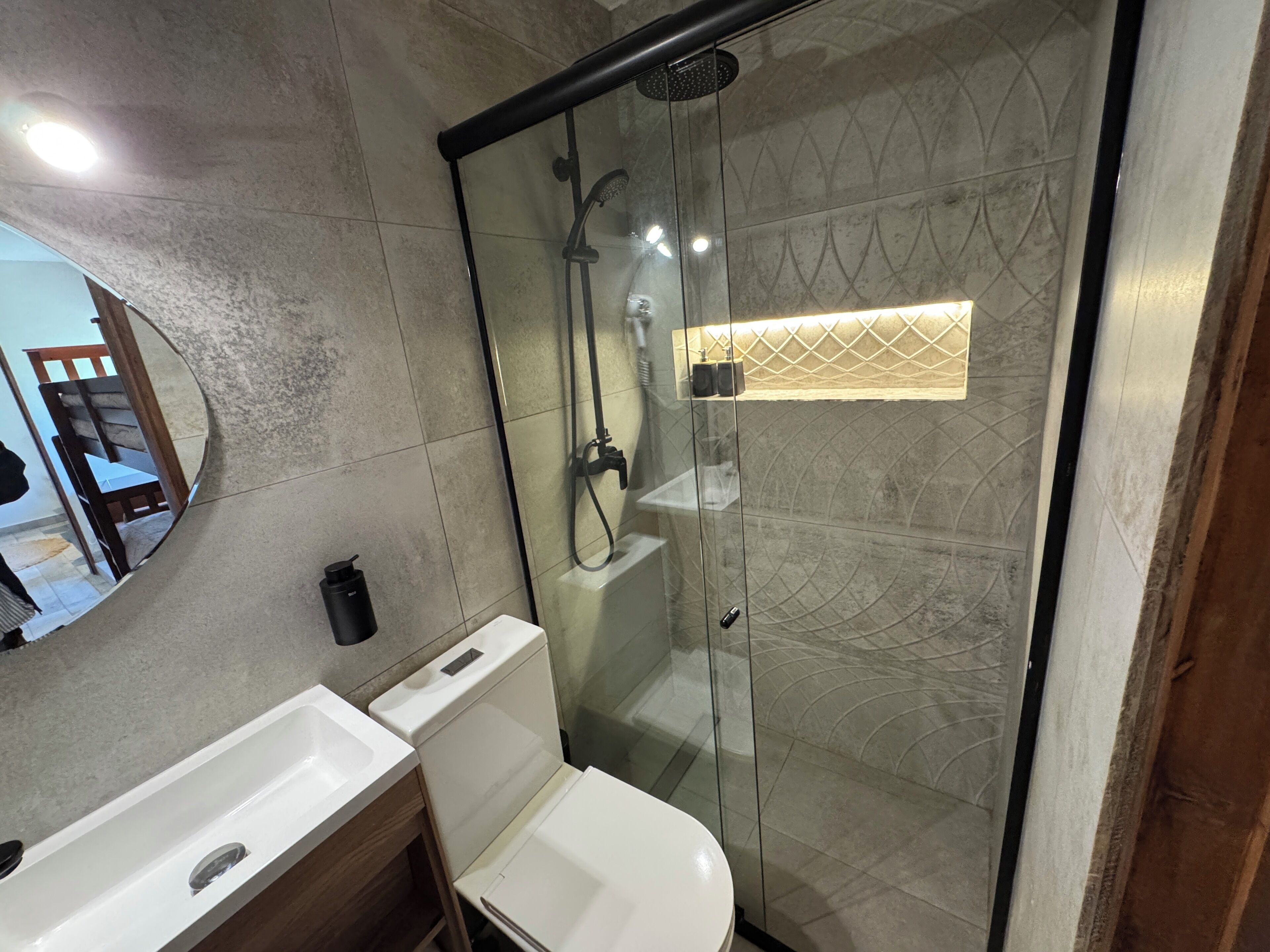 A modern bathroom with a glass-enclosed shower, a white sink, and a toilet.