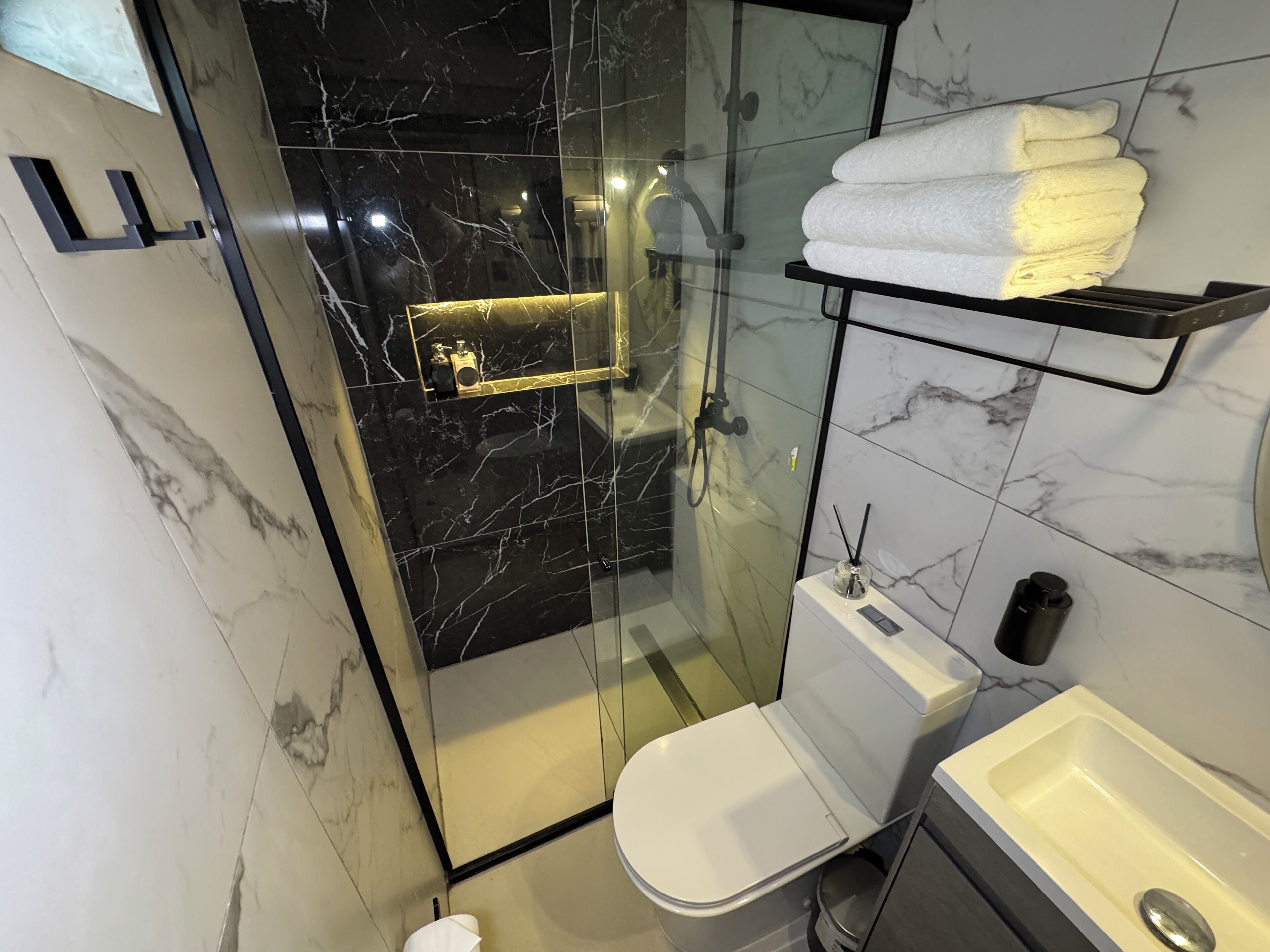A modern bathroom with a glass-enclosed shower, a toilet, and a sink.