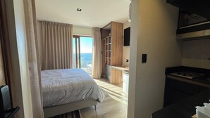 Ein Schlafzimmer mit Bett, Meerblick und einer Küchenzeile.