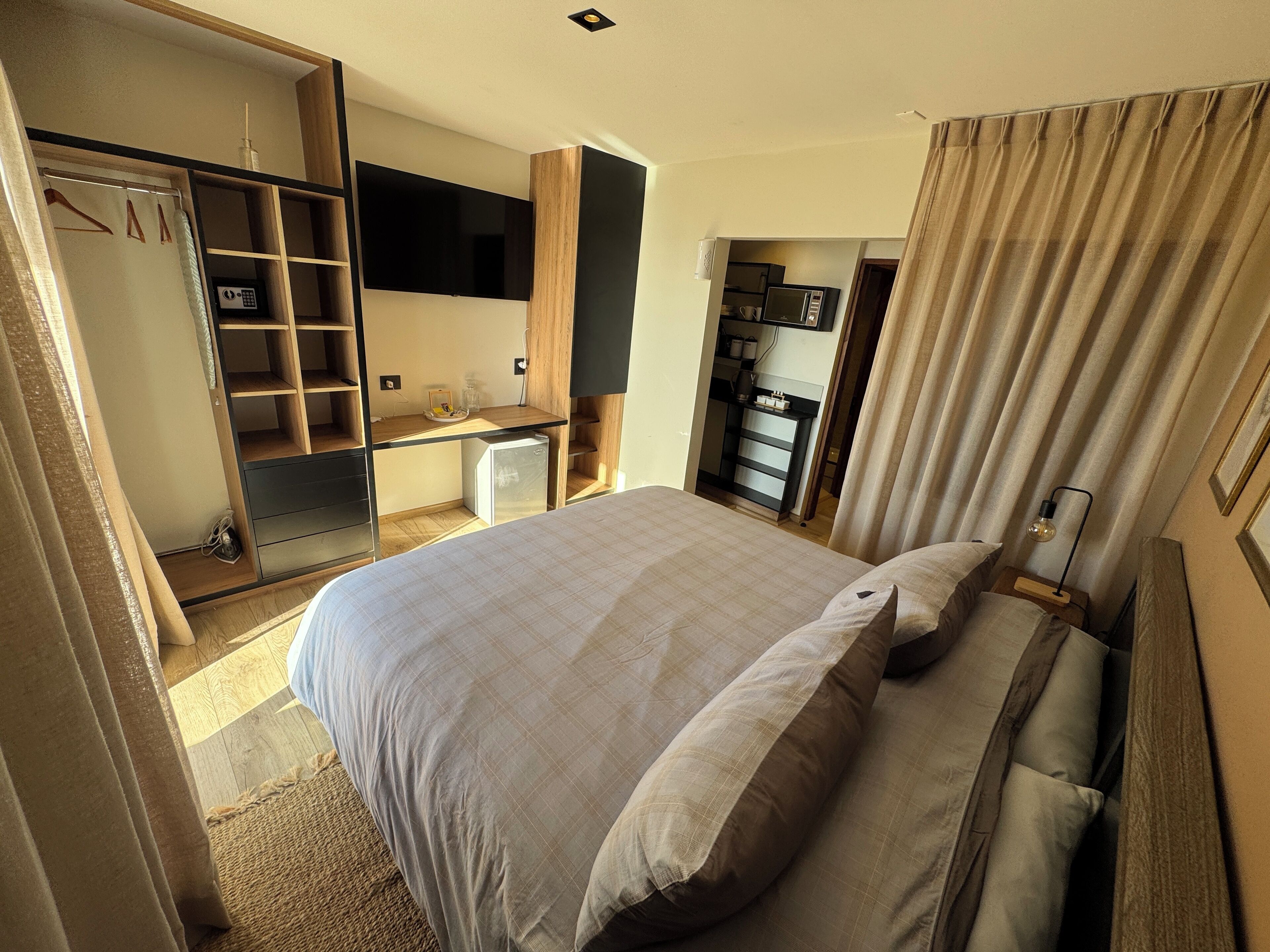 A hotel room with a bed, a desk, a wardrobe, and a television.
