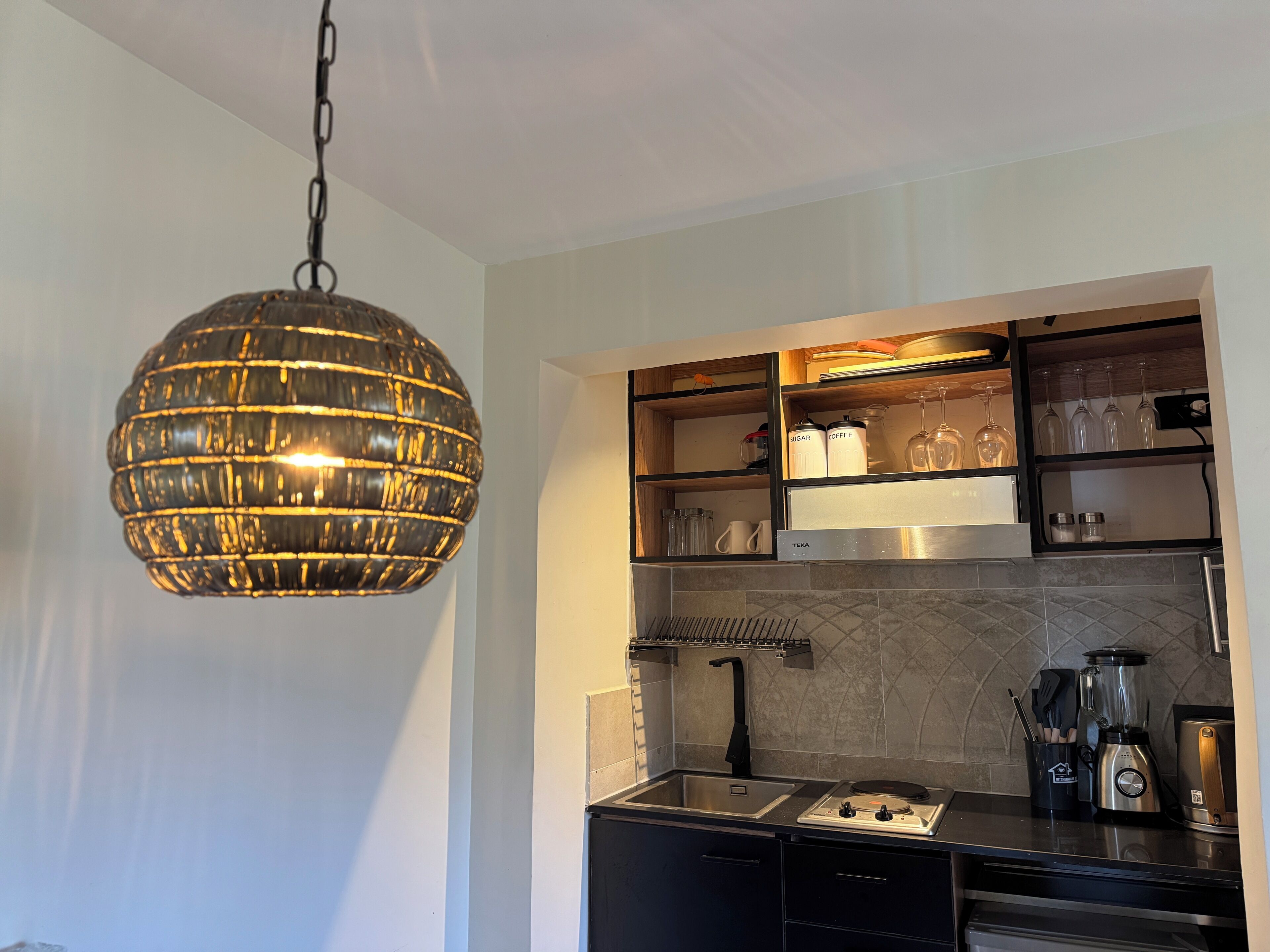 Une cuisine moderne dotée d’un luminaire suspendu, d’étagères intégrées, d’une cuisinière et d’un évier.