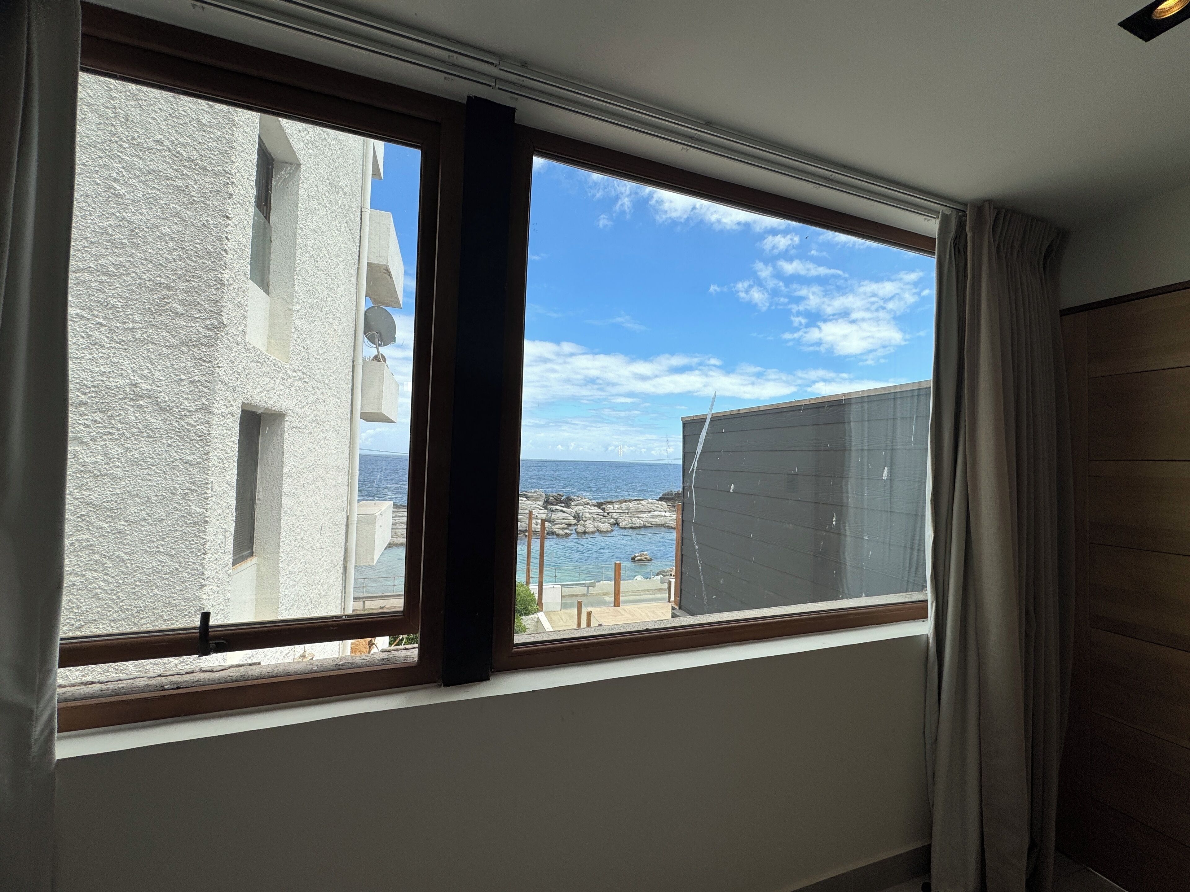 A room with a large window overlooking a rocky coastline and the sea.
