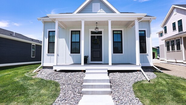 A two-story house with a front porch, a central door, and a small front yard with steps leading to the entrance. - NEW! Sparkling 1-Level 2-BDRM King (Billings)