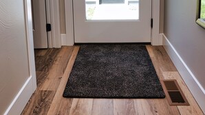 A door with a glass panel, a black doormat, and a vent on the floor. - NEW! Sparkling 1-Level 2-BDRM King (Billings)