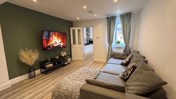 A modern living room with a large TV, a sofa set, and a fireplace. - 3 bed, 'Adrian Cottage' close to Warner Bros, M25, M1. Comes with private gym (Abbots Langley)