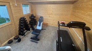 A gym with a bench, dumbbells, a treadmill, and a window. - 3 bed, 'Adrian Cottage' close to Warner Bros, M25, M1. Comes with private gym (Abbots Langley)