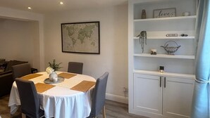 A dining area with a round table, chairs, a world map on the wall, and a white cabinet with shelves. - 3 bed, 'Adrian Cottage' close to Warner Bros, M25, M1. Comes with private gym (Abbots Langley)