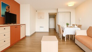 Un soggiorno moderno con televisore, divano, tavolo da pranzo e mobiletti.