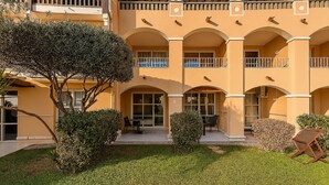 Un edificio a più piani con facciata gialla, diversi balconi e un giardino curato.