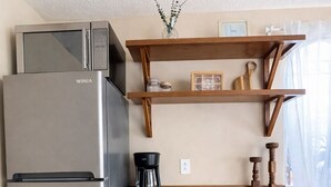 Eine Küche mit einem Edelstahl-Kühlschrank, Holzschränken, einer Kaffeemaschine und einem Regal mit Dekoration.