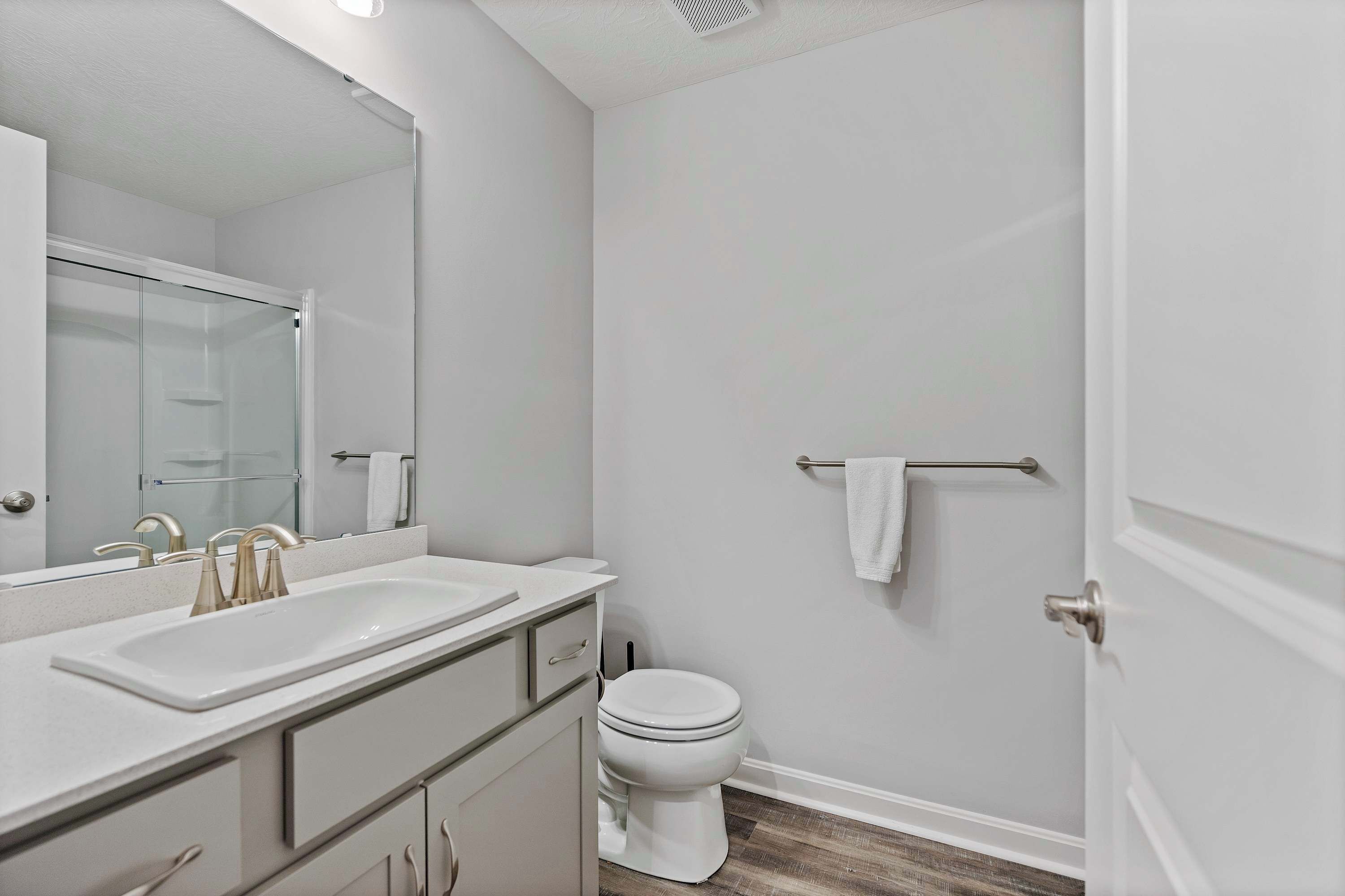 A bathroom with a white sink, mirror, and toilet.