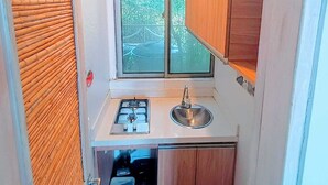 Una cucina compatta con fornello a gas, lavello e mobili in legno.