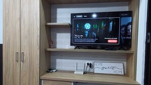 Un mobiletto in legno con una televisione a schermo piatto sopra, un piccolo cassetto e un cartello con scritto “HOME sweet HOME”.