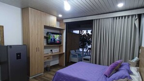 Una camera d'albergo con un letto, una televisione, un armadio in legno e una finestra con tende.