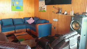 Un espacio habitable pequeño con sofá, una mesita, lavadora y televisión montada en la pared.