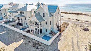 A large, multi-story beachfront property with a swimming pool, multiple balconies, and a beach access road. - NEW! Lux Beachfront, Views, Heated Pool, Sleeps 24 (Panama City Beach)