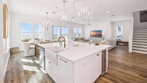 A spacious kitchen with a large island, white cabinetry, and pendant lighting. - NEW! Lux Beachfront, Views, Heated Pool, Sleeps 24 (Panama City Beach)