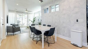 Un espace repas moderne avec une table blanche, des chaises noires et un ventilateur de plafond.