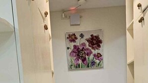 Ein Flur mit einem gerahmten Blumenbild an der Wand, einer Deckenleuchte und einer Tür links.